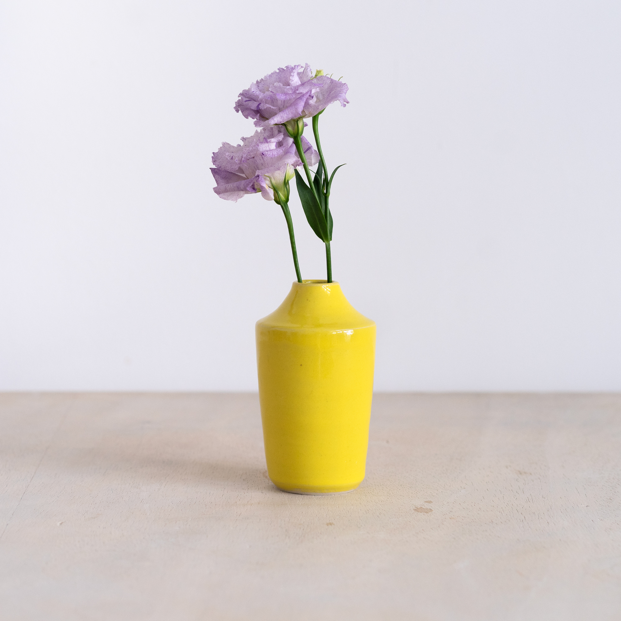 Handgemachte Keramik Vasen Handgemachte schmale Minivase in signalgelb mit zwei lilafarbenen Blumen